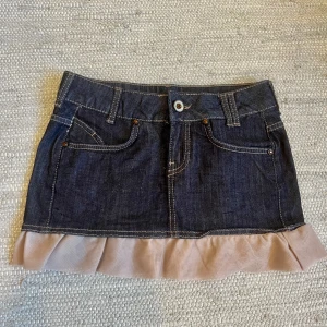 Jeanskjol - Lågmidjad jeanskjol med volang. Midjemått 33 cm rakt över, längd 30 cm. Köp via köp nu❤️