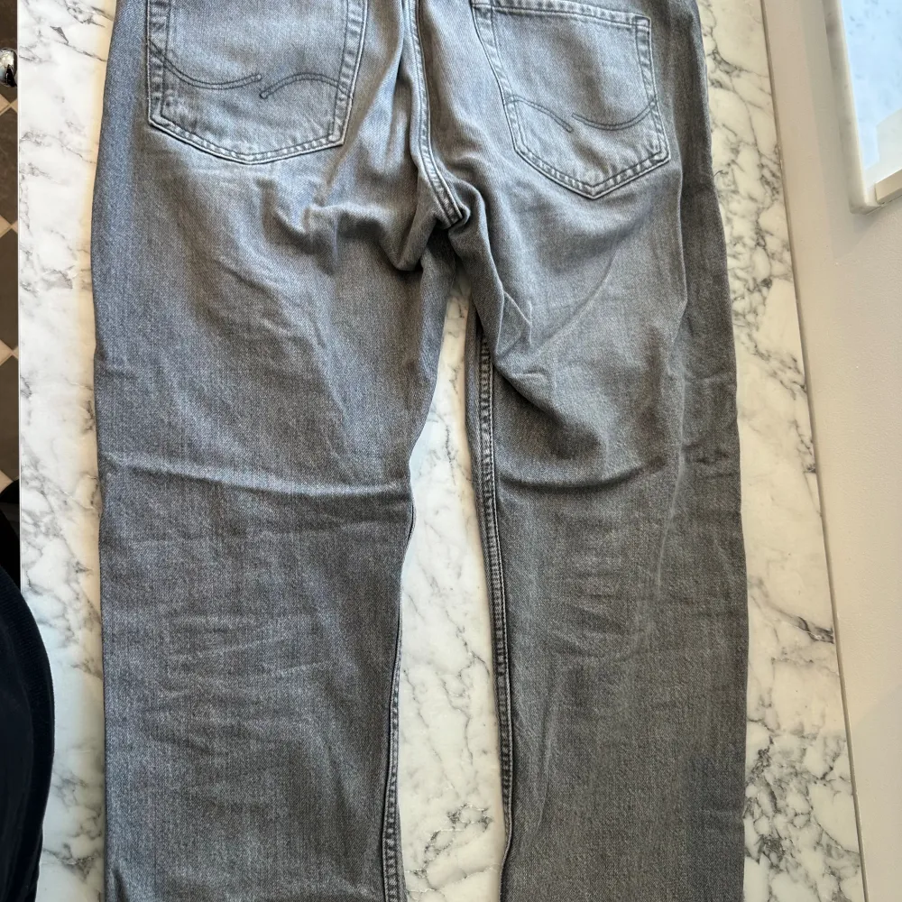 Ett par gråa Jack & Jones jeans i storleken 32/30. Jeansen har använts ett par gånger och är fortfarande i gott skick. Jeansen är av mjukt material, lätt att röra sig med och passar bra med alla olika kläder. Jeansen har nu blivit för små på mig. . Jeans & Byxor.
