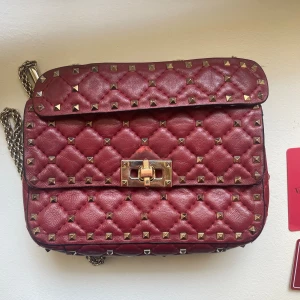 Valentino väska  - Säljer min äkta Valentino väska i röd. Det finns tydliga tecken på användning inuti i väskan, samt vid fästet för kedjan som jag har lagat hos en skomakare. Till utseendet finns inga tydliga defekter som man tänker på. Dustbag samt äktahetstagar!