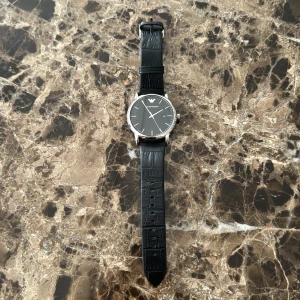 Armani Klocka - En minimalistisk och stilren quartz- och läderarmbandsklocka (43mm diameter) från Emporio Armani. Klockan fungerar som den ska och ordinariepriset ligger på runt 2200-2500kr.