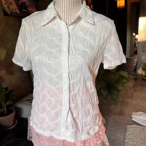 Vit blus - Vit tunn blus. Blusen saknar lapp så vet tyvärr ej vart den är ifrån eller vilken storlek men den uppskattas till ca M.  Ganska genomskinlig så man tänker på det