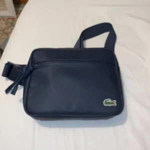 Lacoste väska - En ska använd Max 5 gånger  Har en fläck på baksidan som jag inte lyckats få bort 