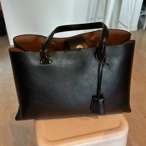 Väska  - Säljer denna fina väskan i konstläder. Den har två stora fack och ett mindre i mitten.  Den är i nyskick då jag aldrig använt den. Den är från Mango och jag köpte den för 650 kr. 