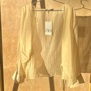 Omlott blus - Nyköpt blus med prislappen kvar, aldrig använts. Genomskinlig, omlott och med knytband på två ställen. I beige och guld färger. Köpt för 379 kr och säljer för 249 kr🫶🏻