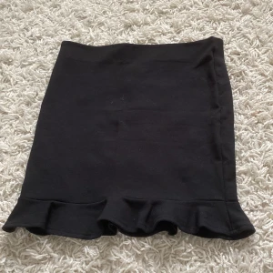 Svart kjol med volang - En svart kjol med volangdetalj vid nederkanten. Kjolen är i storlek 134/140.💕