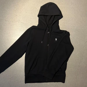 Polo Hoodie - Tja säljer nu en svart Fullzip hoodie från Polo Ralph Lauren i storlek S för endast 599kr! Skick 8/10. Pris är ej hugget i sten hör av er vid funderingar!
