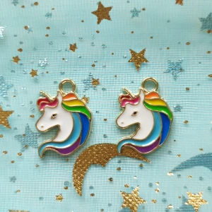 2st regnbågsfärgad enhörning berlock  - Berlocker, hängsmycke, Motiv: enhörning  Färg: vita och regnbågsfärgad, med guldfärgade baksida  Antal: 2st Skick: oanvända,  Går att använda till smyckestillverkning, tex sätta på halsband, armband eller göra örhängen av dem. 