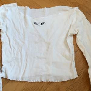 En vit off shoulder tröja med litet tryck frampå. 