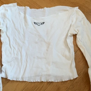 Off shoulder vit tröja  - En vit off shoulder tröja med litet tryck frampå. 