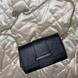 Axelremsväska från Valentino - Liten väska från Valentino med guldkedja och 2 fack. Är i fint skick, men har små defekter på användning. 