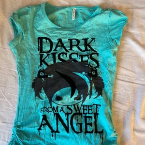 Tshirt med coolt tryck - En åtsittande tshirt med coolt tryck; ”dark kisses from a seeet angel”. Söta detaljer på sidan och på axlarna. 