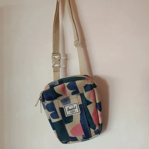 Liten väska, Herschel - Liten väska av märket Herschel, köpt på Hollywood i Göteborg för några år sedan. Använts sparsamt. 20x16 cm. Bra med fack