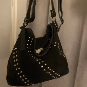 Väska - Funderar på att sälja denna as snygga väska med nitar. Den är lite sliten.  på baksidan finns fläckar, bild 3.Rymlig, jag får plats med min dator. 💕från Wera Stockholm. Har två band. Ett justerbart som går att ta loss och ett vanligt som sitter fast. 