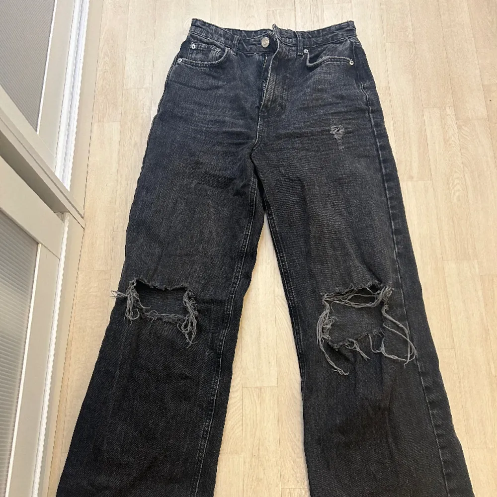 Gråsvarta jeans med utsvängda ben och hål på knäna från ginatricot i storlek 36. I bra skick!. Jeans & Byxor.