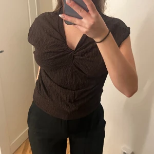 Topp - Kortärmad brun topp med heltäckande textur och knytdetaljer framtill!