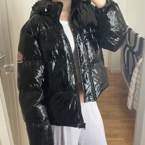 Svart jacka  - Svart glansig jacka, liten defekt i luvan mer går säkert att tvätta bort🤍