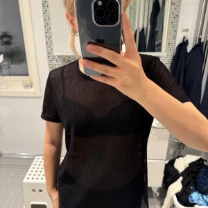 Svart mesh-topp - En svart mesh-topp med korta ärmar. Toppen är genomskinlig, köpt 2 hand utan lapp.