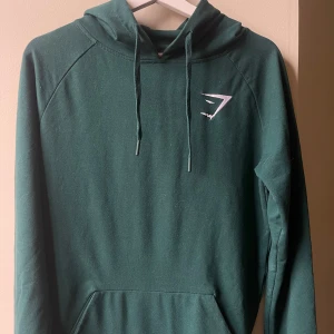 Gymshark Hoodie (S) Mörkgrön - Gymshark hoodie i emeraldgrön. Strl S. Fickor fram och stretchigt material. Ordinarie pris 649kr. Bra skick