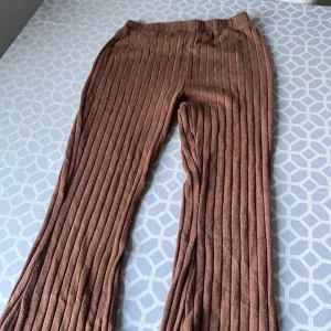 Bruna ribbade byxor från Lindex - Ett par bruna ribbade byxor från Lindex för barn i storlek EUR 146, vilket motsvarar 10-11 år. Byxorna har en bekväm passform och är tillverkade i ett mjukt material.