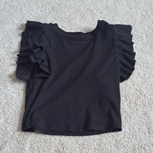Topp - En svart topp med volanger, för liten för mig och inga defekter 