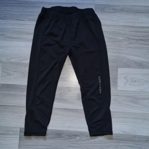 Svarta träningsbyxor från Röhnisch - Ett par svarta träningsbyxor från Röhnisch. Byxorna har en elastisk midja och är tillverkade i ett stretchigt material som ger bra rörelsefrihet. Perfekta för olika typer av träning. stl 150/160