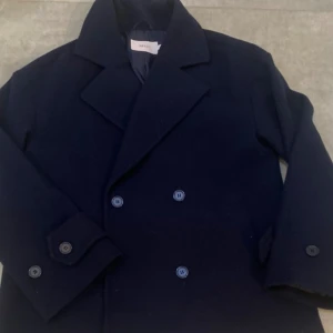 Kort kappa- marinblå  - Kort kappa från Nelly i färgen marinblå. Kappan är i bra skick och är oversize.