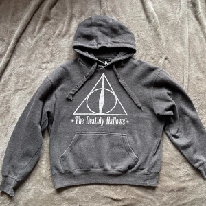 Harry Potter hoodie  - Storlek S, passar exakt på mig (176cm). Använd tröja som tyvärr har en liten missfärgning på baksidan (bild 3) och trasigt snöre från luvan. Annars bra skick och väldigt skön!