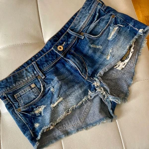Slitna jeansshorts 38  - Snygga slitnajeansshorts 42 cm midja. Låga med snygga detaljer i leopard
