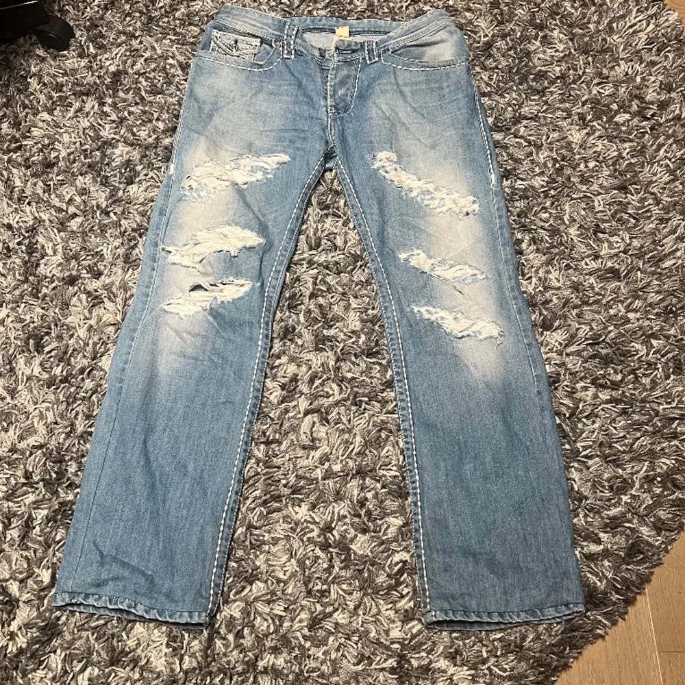 Ett par baggy ljusblåa True Religion Jeans. Skicket ca 7.5/10, finns limrester på insidan av byxorna (inte synligt) och styngnen på taggen där bak har gått upp en aning. Säljer för att de är för små, välkomnar prisförslag.. Jeans & Byxor.
