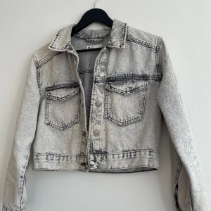 Croppad Jenasjacka - Grå, Croppad jeansjacka från GinaTricot i storlek Xs Använd ett fåtal gånger. Den är solblekt på vissa ställen men inget som märks av när man använder den