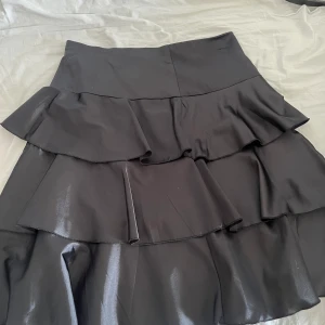 Svart volang kjol - Svart kjol som når lite över knäna. Kmr int ihåg vart jag köpt men den är i strl 38. Använd Ksk 2-3 ggr.