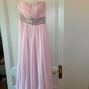 Rosa balklänning - Rosa balklänning/festklänning med glitter/paljetter i midjan. Långklänning/maxiklänning. Slutar i golvet på mig, är 167 cm.  - Använd en gång,  fläckar har uppkommit, behöver nog tvättas på kemtvätt, inget som syns mycket dock. - Köpt för 1600 kr. 