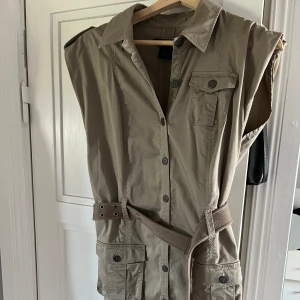 Klänning från Calvin Klein Jeans  - Beige/brun klänning i lite ”äldre stuk” strl M  Knappar längs hela som går att öppna upp och ett midjeband som går att ta bort om det önskas. Väldigt sparsamt använd💕 köparen står för frakten, pris kan diskuteras 