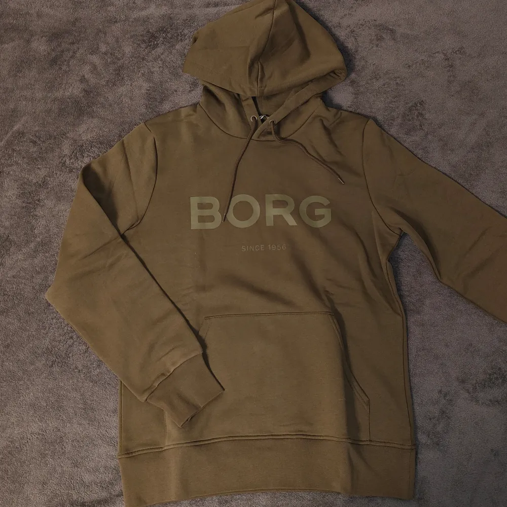 Mörkgrön/olivgrön Björn Borg hoodie i storlek large. Skönt material och varm med bra passform. Säljer då den inte är min stil längre. Helt oanvänd. Skriv vid minsta fundering eller för fler bilder!. Hoodies.