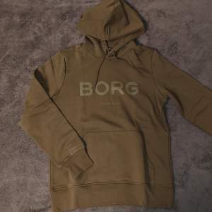 Mörkgrön/olivgrön Björn Borg hoodie i storlek large. Skönt material och varm med bra passform. Säljer då den inte är min stil längre. Helt oanvänd. Skriv vid minsta fundering eller för fler bilder!