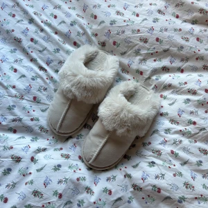 Tofflor  - Säljer nu dessa ljusbeige/vita fluffiga tofflor🧸🧸 de är använda men inga tydliga slit märken. Jag skulle säga att de är små i storleken så passar storlek 38/39