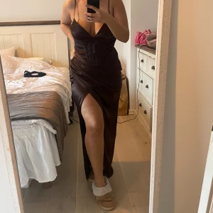 Balklänning - Mörkbrun sexig balklänning från NAKD. I helt nytt skick, aldrig använd, lappen av köpet är kvar. Storlek 42. Lite stor, men största anledningen för försäljning är att jag inte kommer använda den. Vid intresse kan priset diskuteras. 