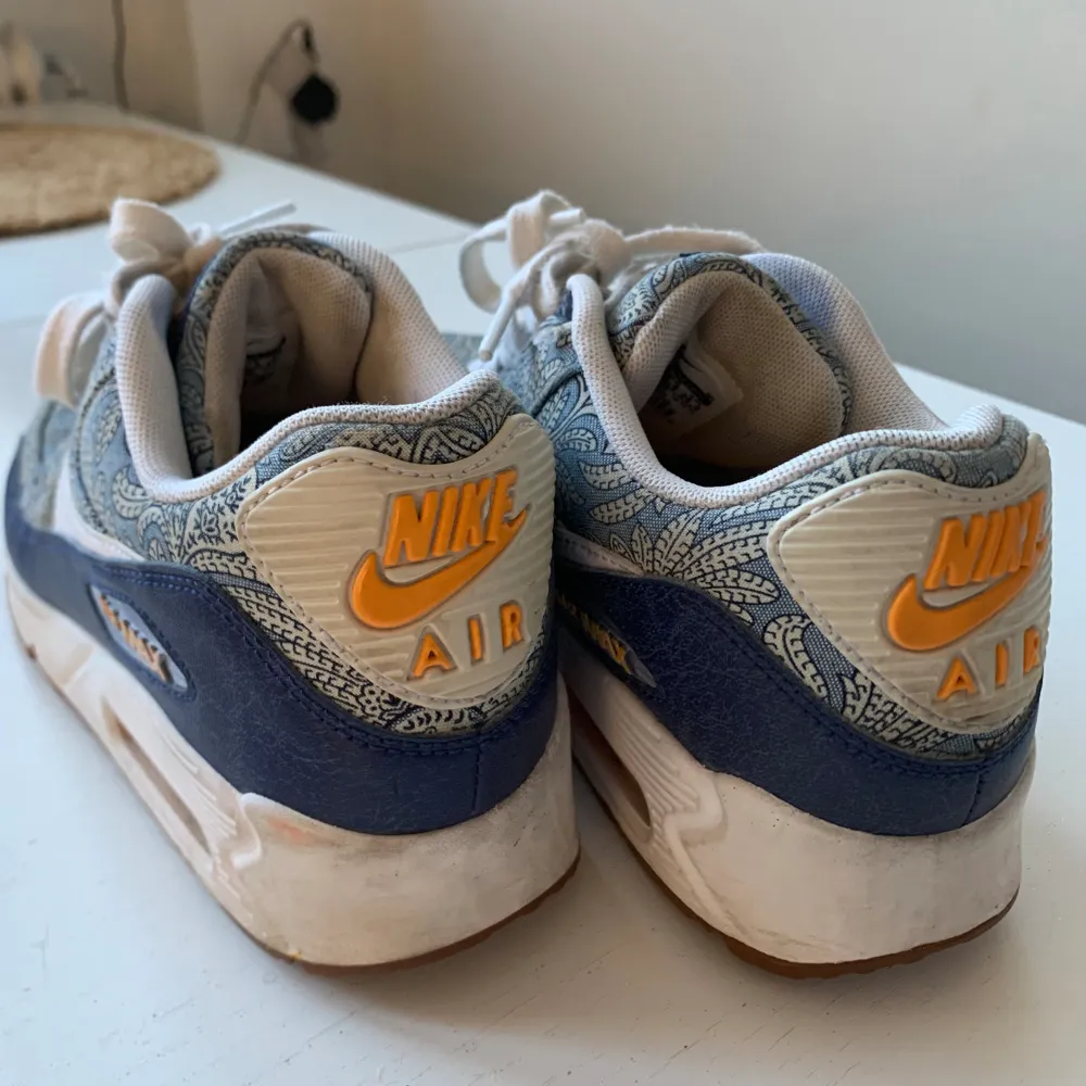 Nike Air Max 90 i blått mönster med gula detaljer. Mycket fina skor i bra skick. Dom är använda men väl bevarade. Skulle må bra av en tvätt på sulorna, storlek 38,5💕. Skor.