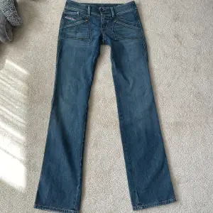 Supersnygga lågmidjade jeans som tyvärr är för långa för mig💓 Storlek 28/32 Midjemåttet rakt över är 39cm Innerbenslängden är 84