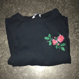 Långärmad tröja - En svart, ribbad och långärmad tröja med en ros på. Säljer för att den börjar bli liten. Den ser ny ut och är ifrån Cubus.