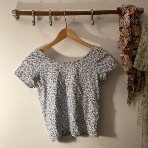 Topp med blå blommor - Otroligt gullig topp med låg rygg, som sitter precis över bhen. Vit med små, blå blommor. 