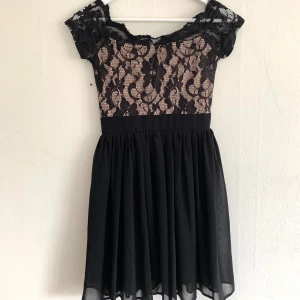 Svart off-shoulder klänning med broderi upptill - Dragkedja i ryggen.