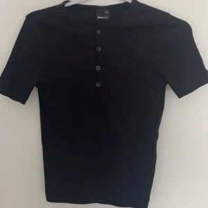 Svart topp - Svart topp med knappar i storlek XXS från Gina tricot, aldrig använd.