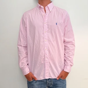 Ralph Lauren - Rosa randig Ralph Lauren skjorta i storlek 16,5-42 vilket motsvara ca L. Skjortan är i fint skick utan några skavanker. Modellen är 186 cm lång. Orginalpris ca 1500 kr och nu endast 499. 