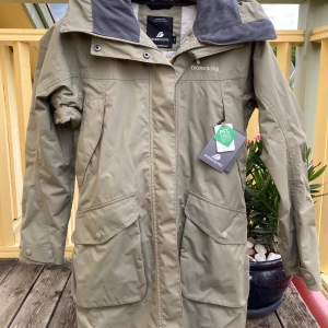 Didrikson Thelma Parka 4 - Den här regnjacka är oanvänd och i nyskick i storlek 36. Sömmarna är tejpade och jackan har en luva som skydd mot vatten och vind.