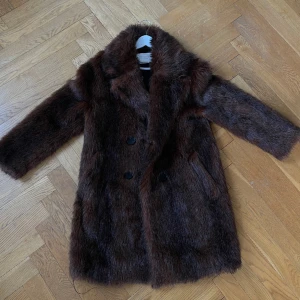 Pälsjacka  - Fake pälsjacka som går ner till knäna,  har lite defekter som finns med på bild; men det är inget som man kan se utåt. 
