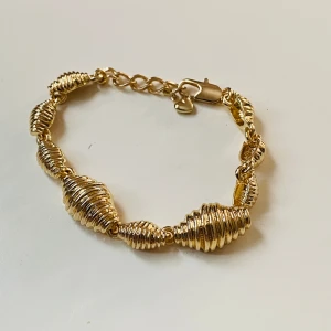 Armband  - Vackert guldfärgat armband i gott skick  Okänt material 