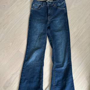 Mörkblåa jeans med slits på baksidan av jeansen nere vid ”hälen” 