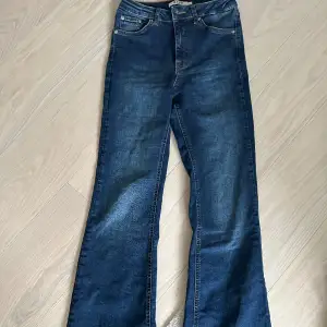 Mörkblåa jeans med slits på baksidan av jeansen nere vid ”hälen” 