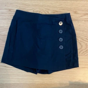 Svart byxkjol - Svart byxkjol med knappar framtill. Storlek 36 från Bershka